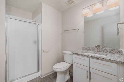 A white bathroom with a toilet, sink, and shower.
