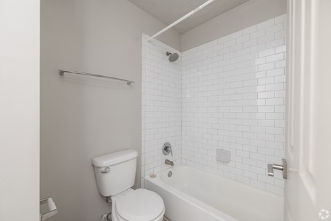 A white toilet sits next to a white bathtub in a bathroom.