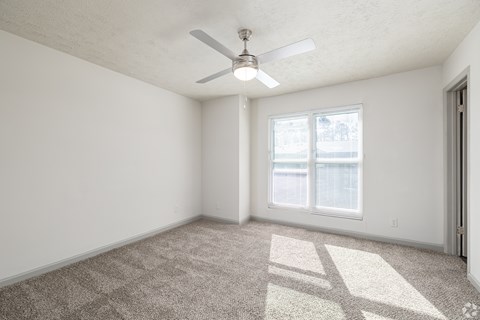 A room with a ceiling fan and carpeted floor.