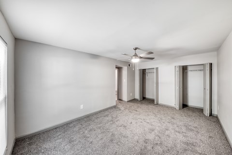 A room with a ceiling fan and carpeted floor.