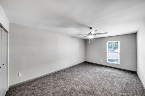 A room with a ceiling fan and a window showing a body of water.