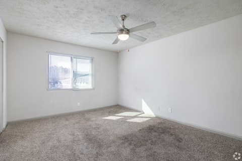 A room with a ceiling fan and carpeted floor.