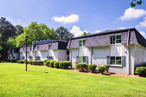 A white house with a grey roof and a green lawn in front.