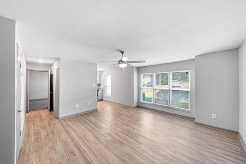 A spacious room with wooden flooring and a ceiling fan.
