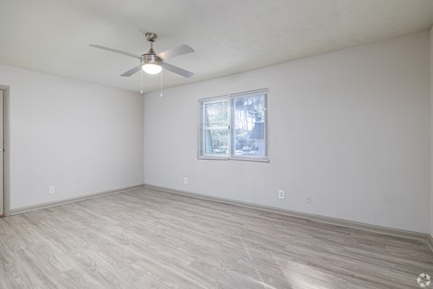 A room with a ceiling fan and a window with blinds.