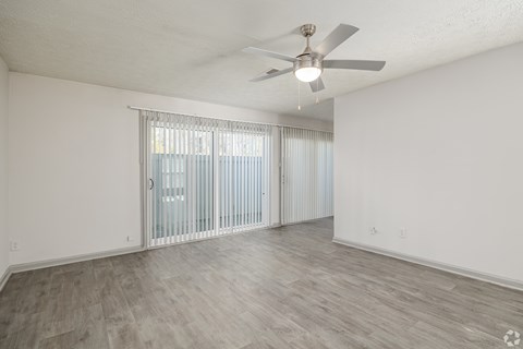 A room with a ceiling fan and sliding glass doors.