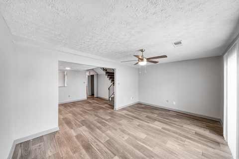 A room with a ceiling fan and wooden flooring.