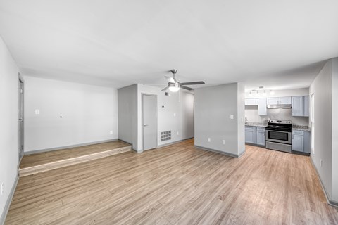 A spacious room with a wooden floor and a ceiling fan.