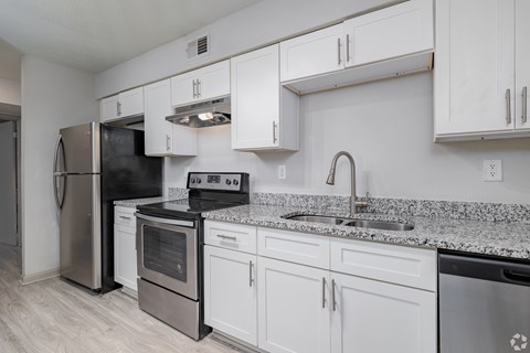 A kitchen with white cabinets and a granite countertop.