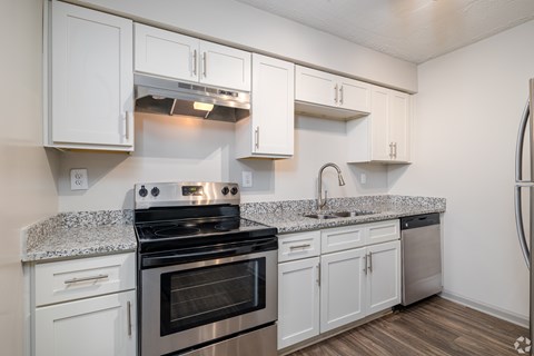 A kitchen with white cabinets and a granite countertop.