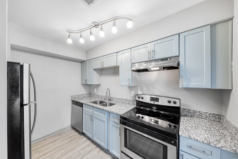 A kitchen with a black refrigerator and a granite countertop.