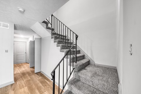 A staircase with a black railing and a grey carpeted stair runner.