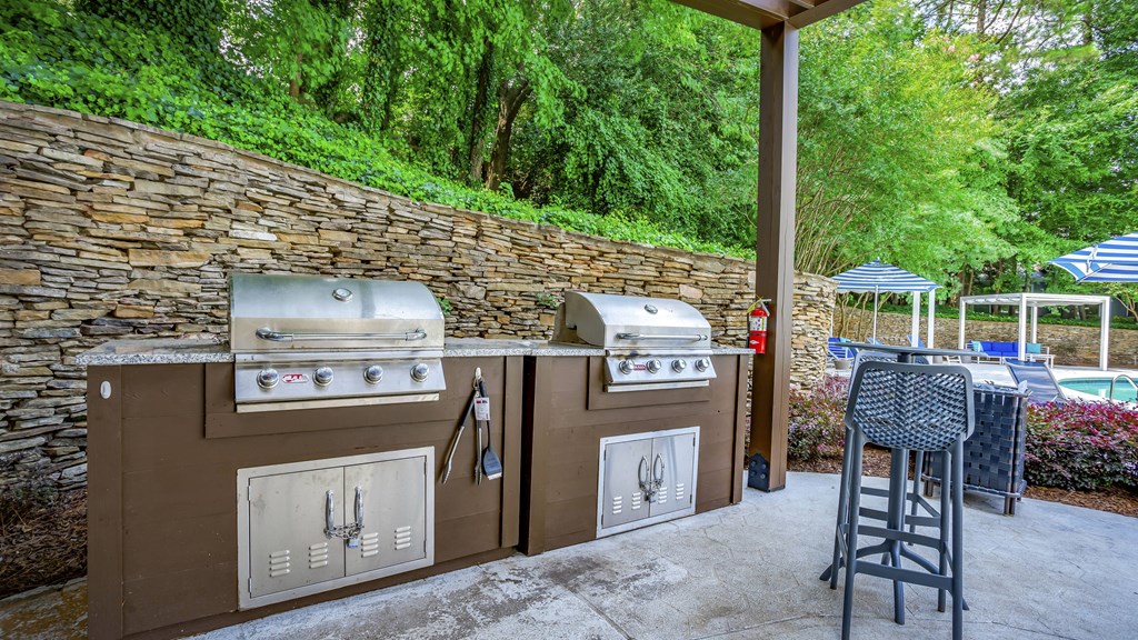 a patio with a barbecue grill and a table with chairs