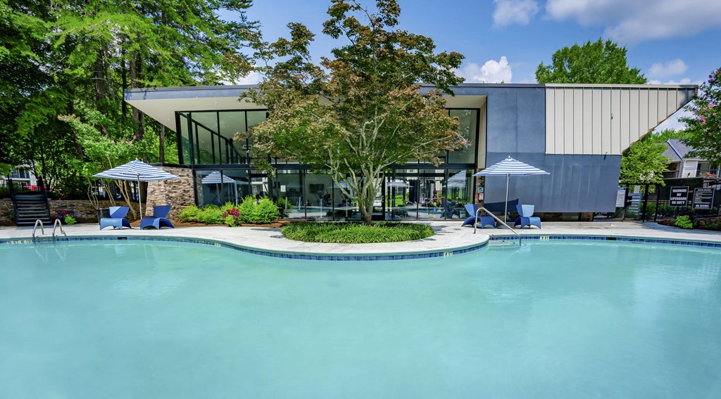a swimming pool with chairs and umbrellas near a building