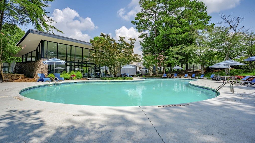 a swimming pool in front of a building with umbrellas