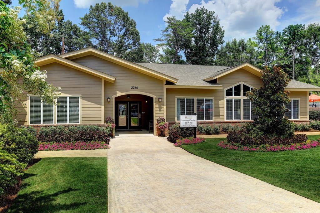 a house with a sidewalk in front of a lawn and trees