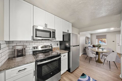 A kitchen with white cabinets and a black refrigerator.