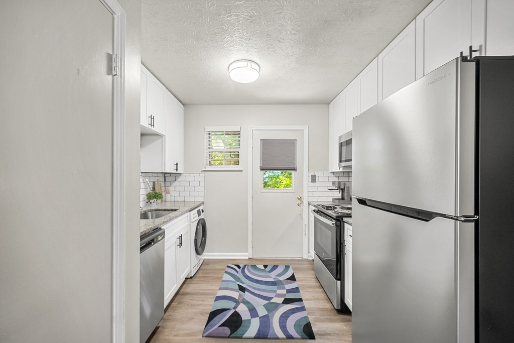 A kitchen with a black fridge and a white door.
