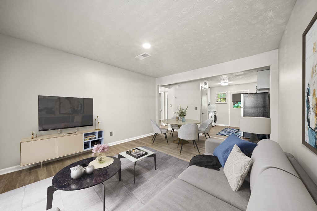 A living room with a grey couch, a black coffee table, and a flat screen TV mounted on the wall.
