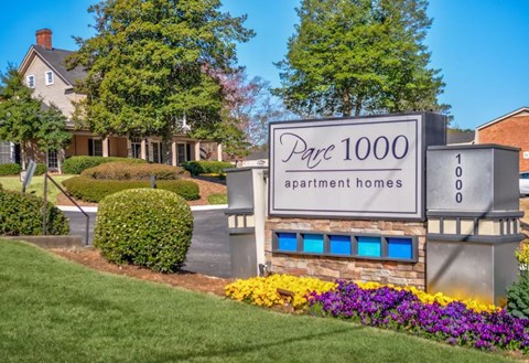 A sign for a 1000 apartment homes sits in front of a building.