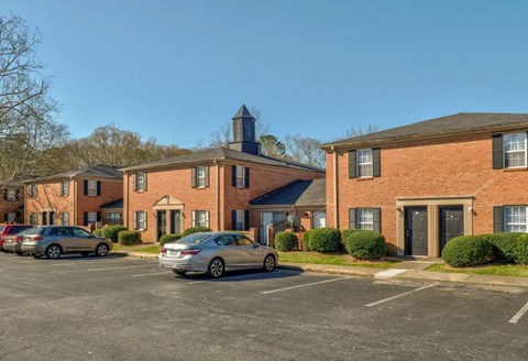 A parking lot with cars and a building with a tower in the background.