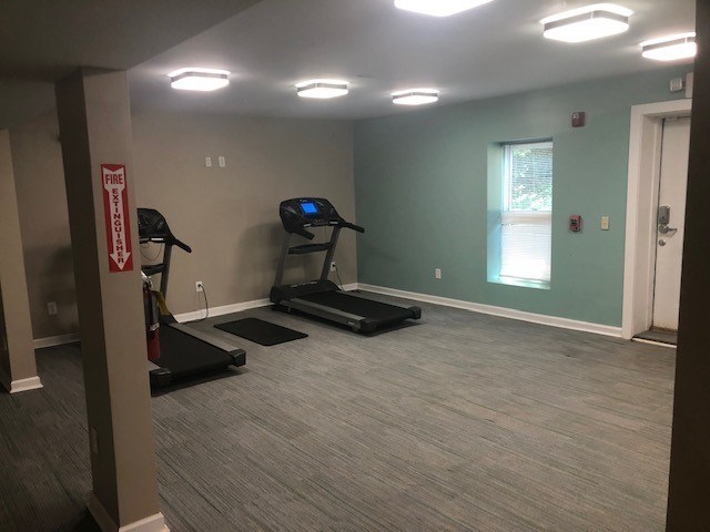 A gym with treadmills and a fire exit sign.