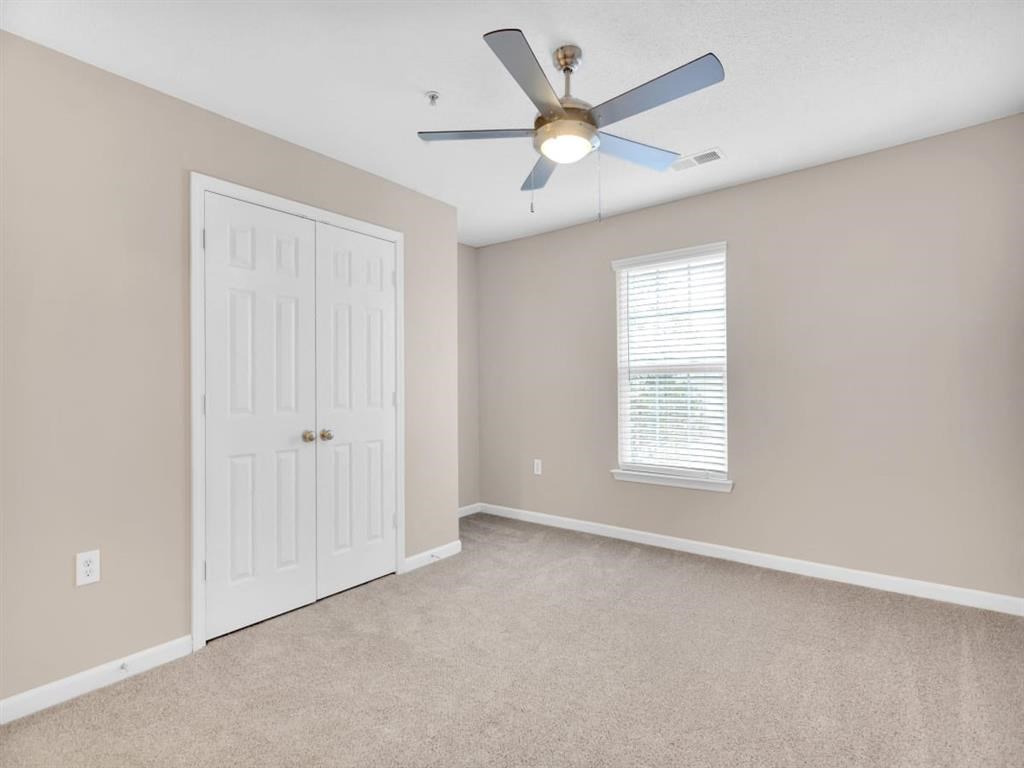 an empty bedroom with a ceiling fan and a door