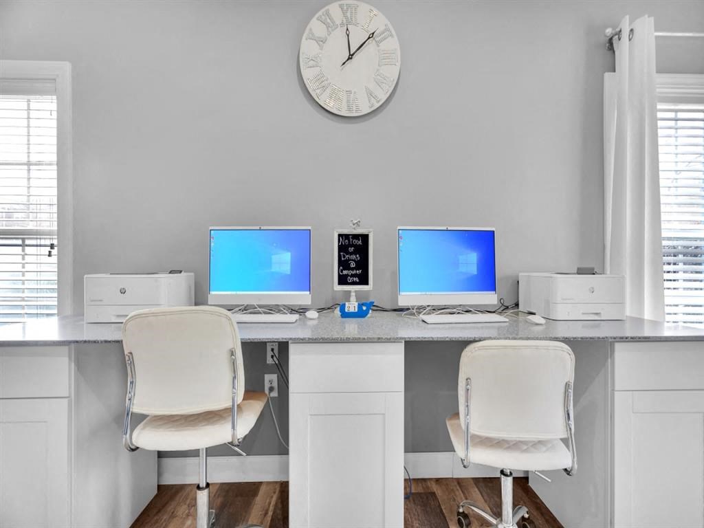 an office with two computers and a clock on the wall