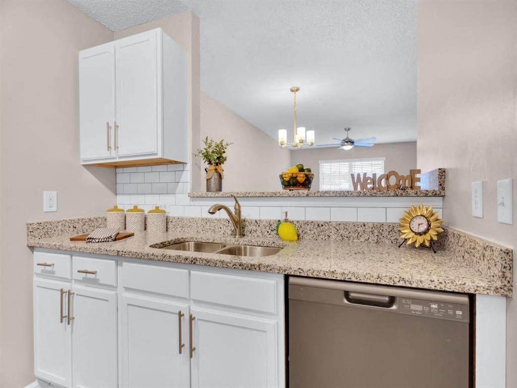 a kitchen with white cabinets and granite counter tops and a dishwasher