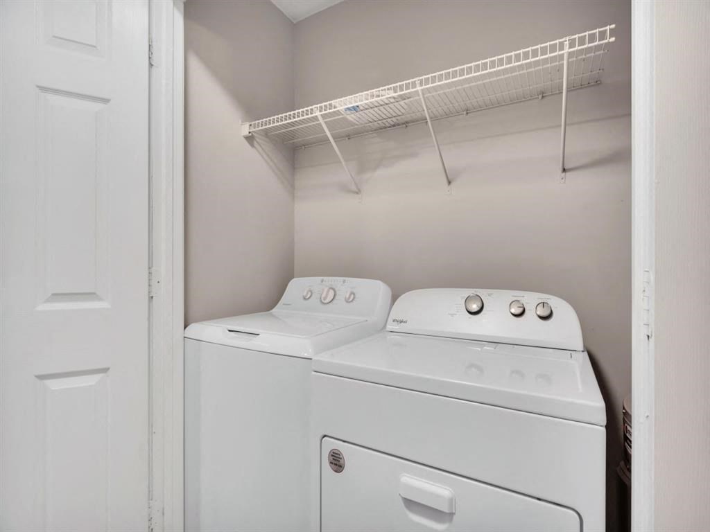 a washer and dryer in a white room with a shelf on the wall