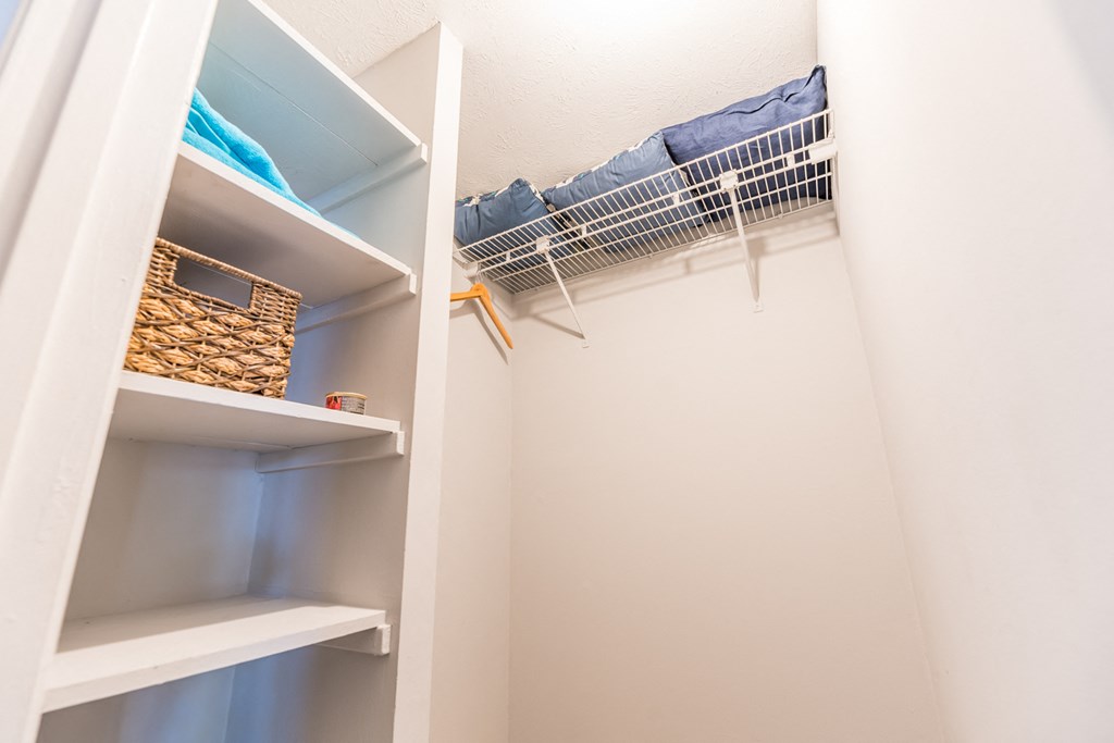 a walk in closet with shelves and a rack of clothes