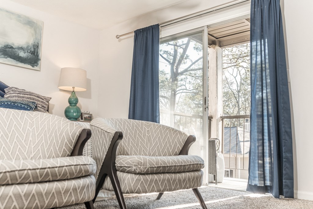 a living room with a couch and chairs and a door to a balcony