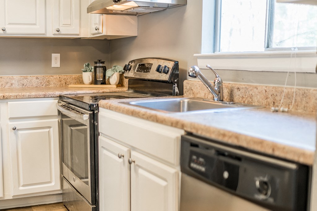 a kitchen with white cabinets and a sink and a stove