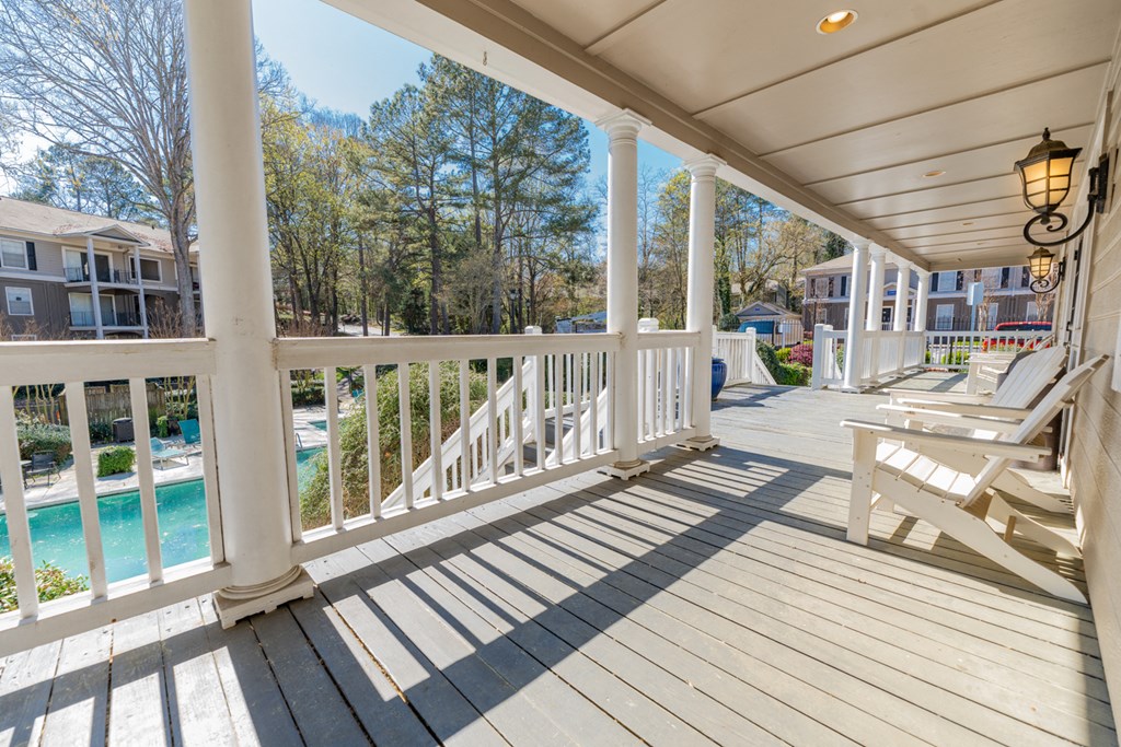 a covered porch with two white rocking chairs and a pool