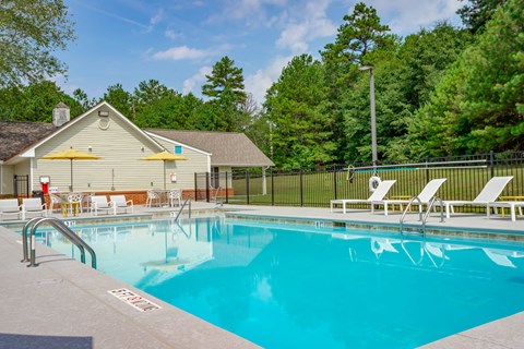 a swimming pool with chairs and a house in the background
