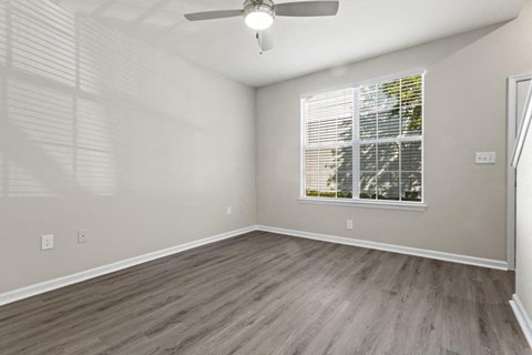 an empty living room with a large window and wooden floors