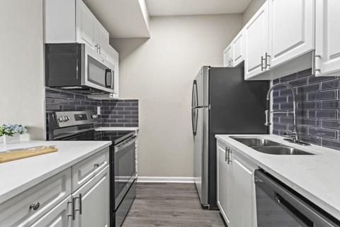 a kitchen with white cabinets and black appliances
