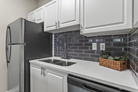 a kitchen with white cabinets and a sink and a refrigerator
