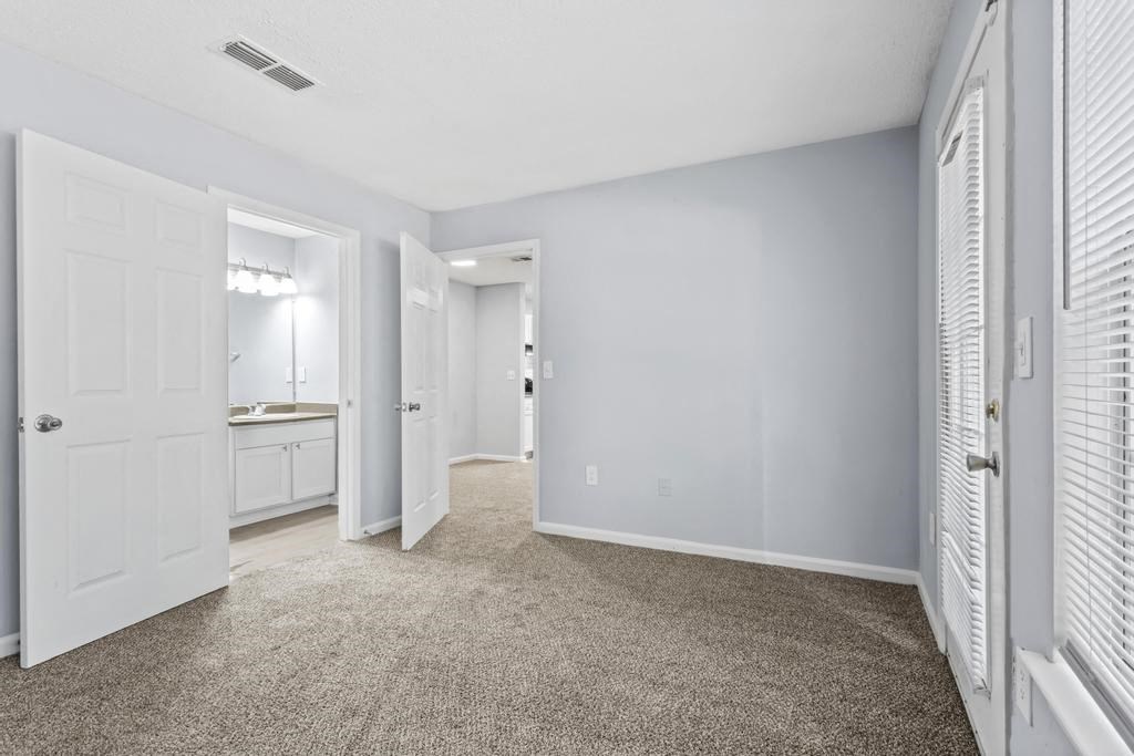 an empty bedroom with white doors and a bathroom
