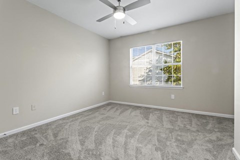 an empty room with a window and a ceiling fan