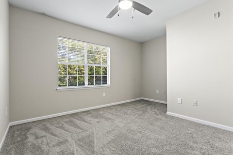 an empty room with a window and a ceiling fan
