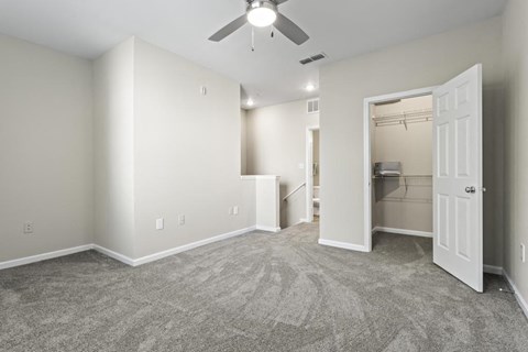 an empty living room with a ceiling fan and a closet