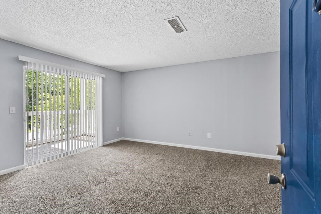 an empty living room with a blue door and a balcony
