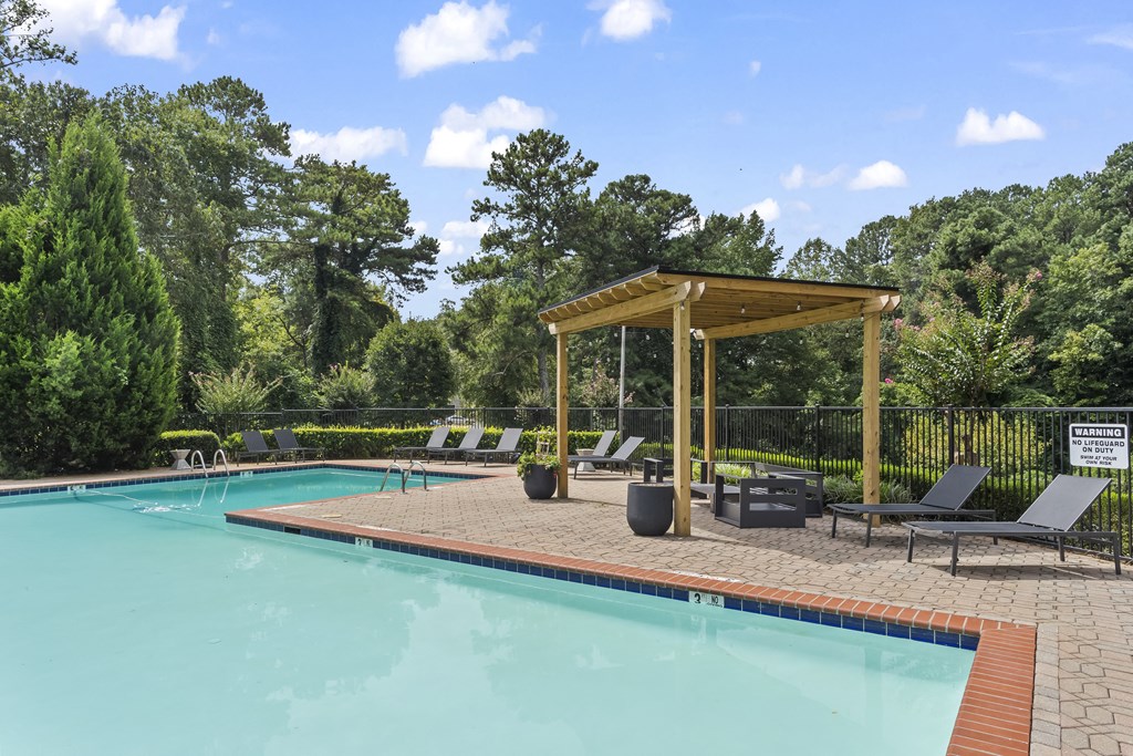 a swimming pool with lounge chairs and a wooden pavilion