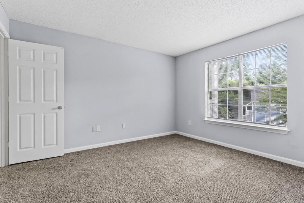 an empty bedroom with a window and a white door