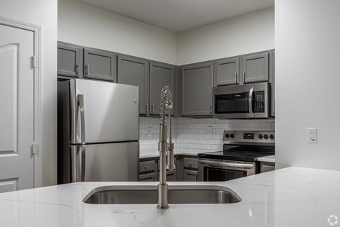 A kitchen with a stainless steel refrigerator, microwave, and oven.