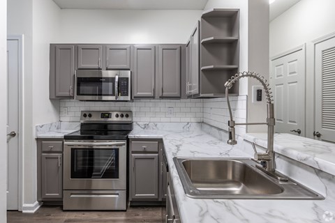A kitchen with a stove, oven, microwave, and sink.