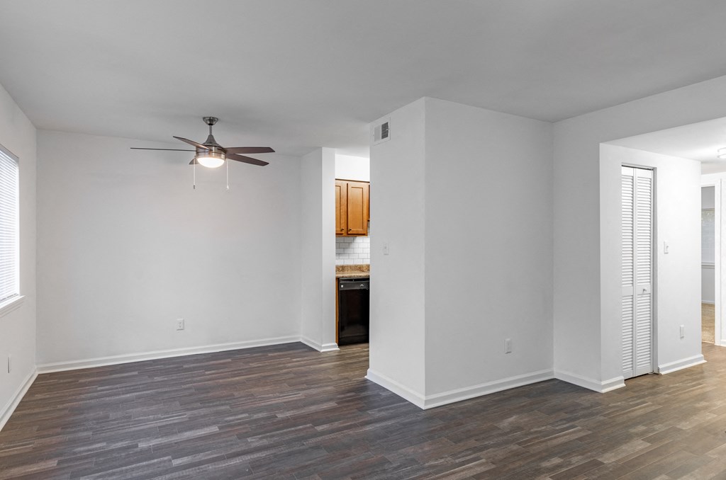 an empty living room with white walls and a ceiling fan