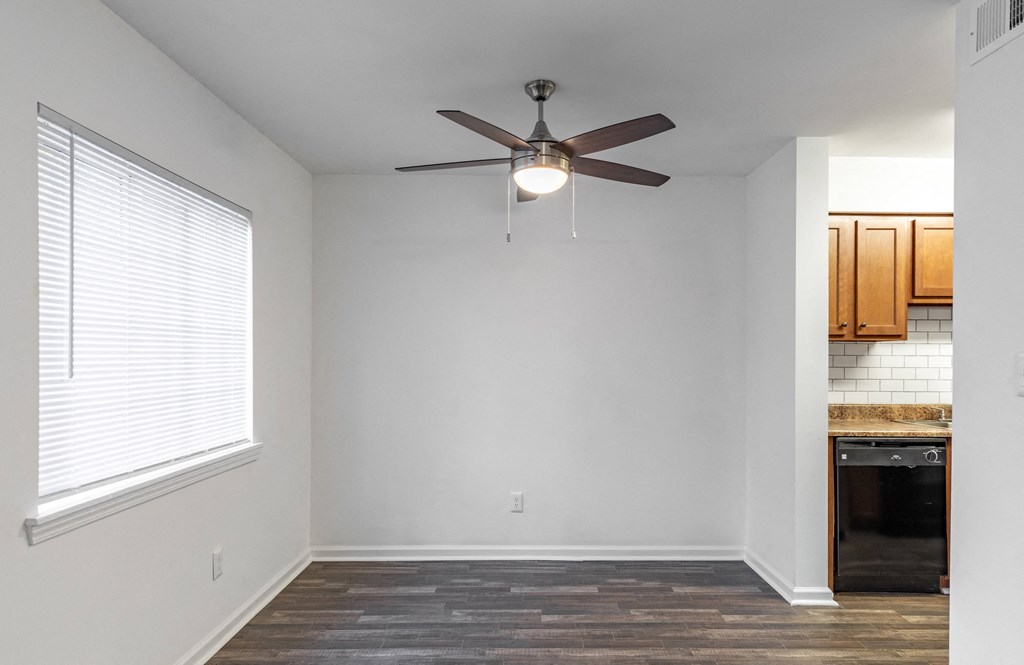 an empty living room with a ceiling fan and a window