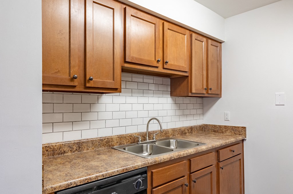 an empty kitchen with a sink and wooden cabinets